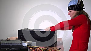 Technician girl remove motherboard from desktop computer and examine it