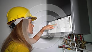 Technician girl servicing gas boiler for hot water and heating