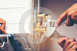 Technician hand using fix wrench to tighten outdoor unit of air