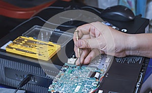 technician hand using screwdriver to assembling the motherboard of laptop computer