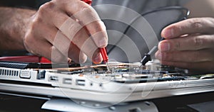 Technician hands checking motherboard with multimeter