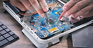 Technician hands checking motherboard with multimeter