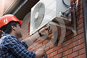 Technician in hardhat connecting outdoor air conditioning unit