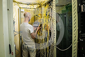 The technician with the help of an oscillograph measures the level of the optical cable signal in the server room of the data