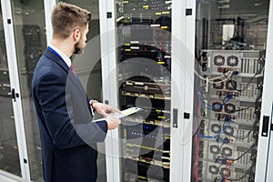 Technician holding clipboard while analyzing server