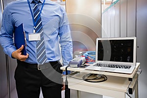 Technician holding clipboard standing near table