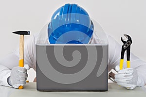 Technician Holding Hammer And Plier With Laptop