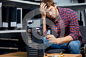 IT technician holding his forehead and repairing broken pc computer