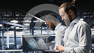 Technician holding laptop walking on server farm platform