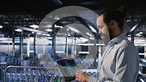 Technician holding laptop walking on server farm platform