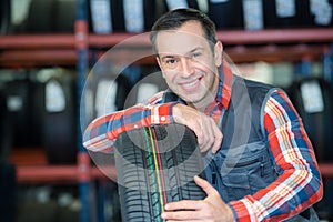 technician holding with new tyre for car in tire shop