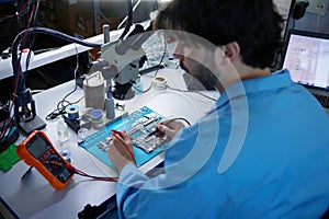 Technician actively engaged in critical work on circuit board while observing under a microscope