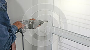 Technician uses an electrical drilling machine by hand to work at a window