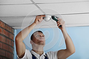 Technician installing CCTV camera on ceiling