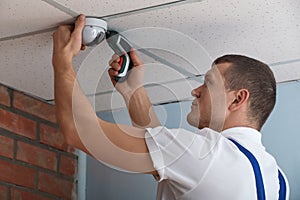 Technician installing CCTV camera on ceiling