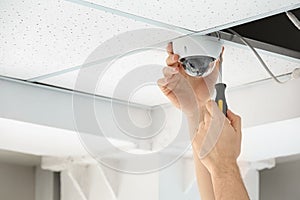 Technician installing CCTV camera on ceiling indoor