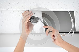 Technician installing CCTV camera on ceiling indoors