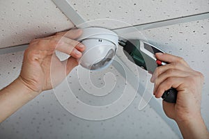 Technician installing CCTV camera on ceiling indoors, closeup