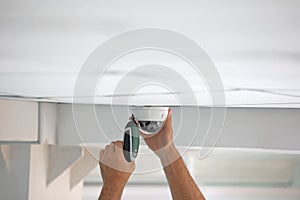 Technician installing CCTV camera on ceiling indoors