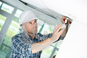 Technician installing cctv camera on ceiling indoors