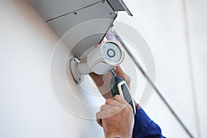 Technician installing CCTV camera on wall, closeup