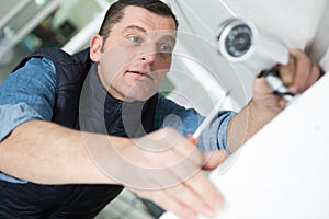 technician installing cctv camera on wall indoors