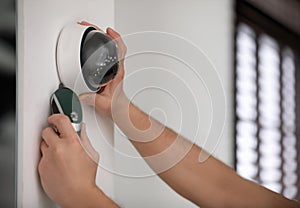 Technician installing CCTV camera on wall indoors