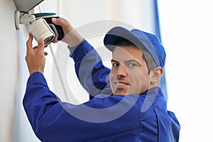 Technician installing CCTV camera on wall outdoors