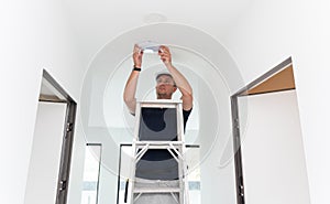 technician is installing an LED spotlight in the ceiling.