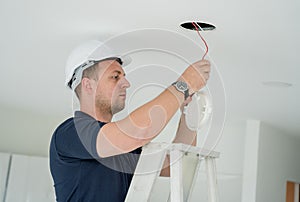 technician is installing an LED spotlight in the ceiling.