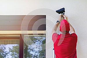 Technician installing outdoor security surveillance camera on house exterior wall