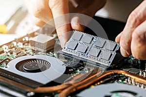 Technician installing ram memory module in laptop motherboard. computer upgrade