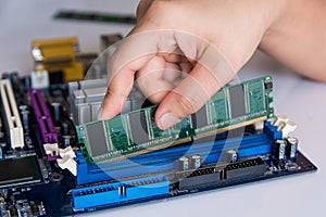 Technician installing RAM stick (random access memory) to socket
