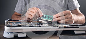 Technician installing random access memory on laptop computer
