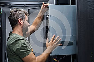 It technician installing a server in a data center rack performing hardware maintenance and network setup