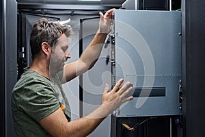 It technician installing server hardware in a data center rack performing maintenance and network setup