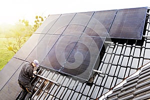 Technician installing solar panels on the roof of a house