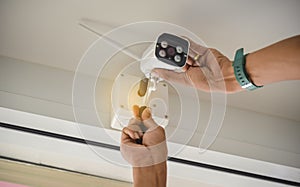 Technician installing wireless CCTV camera by screwed for home security system and installed w