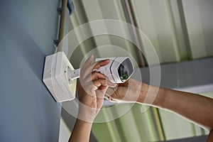 Technician installing wireless CCTV camera by screwed for home security system and installed w