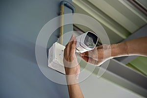 Technician installing wireless CCTV camera by screwed for home security system and installed w