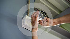 Technician installing wireless CCTV camera by screwed for home security system and installed w