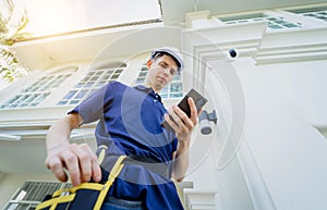 A technician installs a CCTV camera on the facade of a residential building.