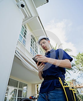 A technician installs a CCTV camera on the facade of a residential building.