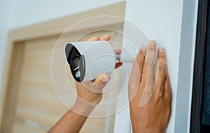 A technician installs a CCTV camera in a modern apartment.