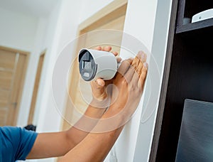 A technician installs a CCTV camera in a modern apartment.