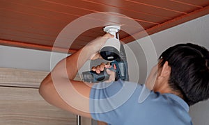 A technician installs a CCTV camera in a modern apartment.