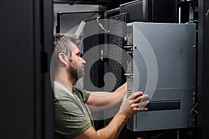 IT technician installing server hardware in a data center rack performing maintenance and network setup
