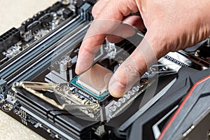 A technician installs an Intel i7-9700K CPU in 1151 socket on a Gigabyte motherboard. PC assembly and upgrade concept photo