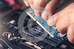 The technician is laying a RAM on the socket of the computer motherboard.