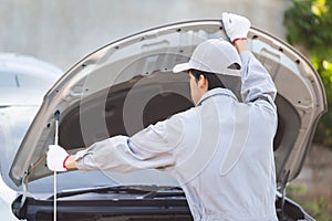 Technician man checks and fixes car air conditioner system, Auto mechanic repairs a car with an open hood, Car repairs